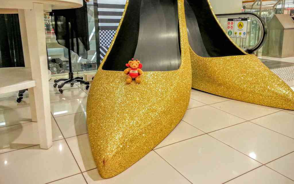 BeeBear tries on a pair of golden dancing shoes. They are a bit too big.