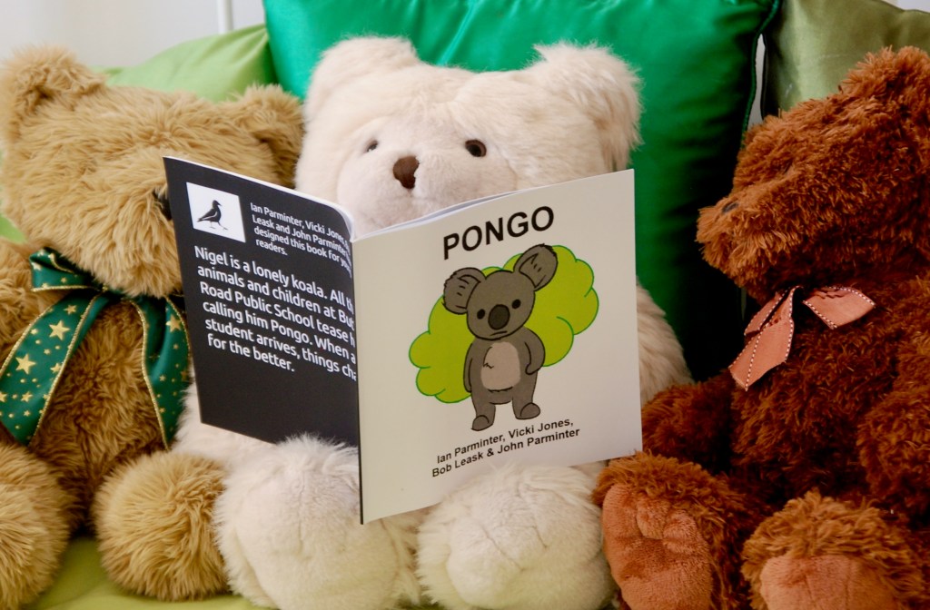 The book Pongo being read by teddybears sitting up against green cushions